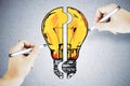 Two hands with pen drawing yellow light bulb puzzle Royalty Free Stock Photo