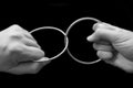 Two hands pulling rings apart that are joined together Royalty Free Stock Photo