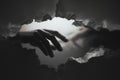 Two hands reaching through a torn paper barrier in a black and white composition showcasing connection and longing Royalty Free Stock Photo