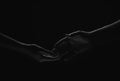 Two hands reaching toward. Helping hand outstretched for salvation on isolated black background. Close up of man and Royalty Free Stock Photo