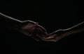 Two hands reaching toward. Helping hand outstretched for salvation on isolated black background. Close up of man and Royalty Free Stock Photo