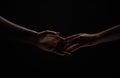 Two hands reaching toward. Helping hand outstretched for salvation on isolated black background. Close up of man and Royalty Free Stock Photo