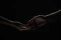 Two hands reaching toward. Helping hand outstretched for salvation on isolated black background. Close up of man and Royalty Free Stock Photo