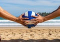 Two hands reaching for a volleyball on a sandy beach with ocean background Royalty Free Stock Photo