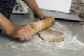 Two hands rolling, the biscuit dough evenly over flour with a rolling pin, making cookies and gingerbread in the kitchen Royalty Free Stock Photo