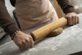 Two hands rolling, the biscuit dough evenly over flour with a rolling pin, making cookies and gingerbread in the kitchen Royalty Free Stock Photo