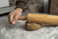 Two hands rolling, the biscuit dough evenly over flour with a rolling pin, making cookies and gingerbread in the kitchen Royalty Free Stock Photo