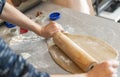 Two hands rolling, the biscuit dough evenly over flour with a rolling pin, making cookies and gingerbread in the kitchen Royalty Free Stock Photo