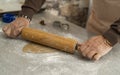 Two hands rolling, the biscuit dough evenly over flour with a rolling pin, making cookies and gingerbread in the kitchen Royalty Free Stock Photo