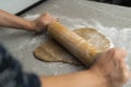 Two hands rolling, the biscuit dough evenly over flour with a rolling pin, making cookies and gingerbread in the kitchen Royalty Free Stock Photo