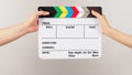 Two hands send and hold rainbow clapper board or movie slate on white background