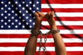 Two hands shackled a metal chain on the background of the USA flag