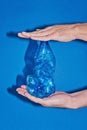 Two hands squeezing plastic bottle on blue background. Zero waste cocnept Royalty Free Stock Photo