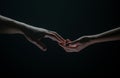 Two hands stretch each other, black background. Couple in love holding hads, close up. Helping hand, support, friendship Royalty Free Stock Photo