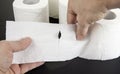 Two hands tear up toilet paper