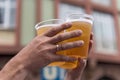 Two hands and three full plastic cups with beer