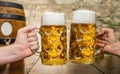 Two hands toasting with glasses with german beer and wooden barrel, Munich, Germany Royalty Free Stock Photo