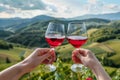 Two hands toasting with red wine glasses against the backdrop of green hills and mountains. Generative AI Royalty Free Stock Photo