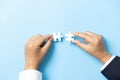 Two hands trying to connect couple puzzle piece on blue background. Teamwork concept. Closeup hand of connecting jigsaw puzzle Royalty Free Stock Photo