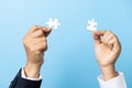 Two hands trying to connect couple puzzle piece on blue background. Teamwork concept. Closeup hand of connecting jigsaw puzzle Royalty Free Stock Photo