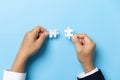 Two hands trying to connect couple puzzle piece on blue background. Teamwork concept. Closeup hand of connecting jigsaw puzzle Royalty Free Stock Photo