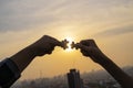 Two hands trying to connect couple puzzle piece with sunset background. Jigsaw alone wooden puzzle against sun rays Royalty Free Stock Photo