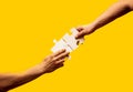 Two hands trying to connect couple puzzle piece on yellow background. Teamwork concept. Closeup hand of connecting Royalty Free Stock Photo