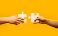 Two hands trying to connect couple puzzle piece on yellow background. Teamwork concept. Holding puzzle. Closeup hand of