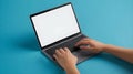 Two hands are typing on a laptop keyboard with a blank white screen. The laptop is on a blue surface Royalty Free Stock Photo