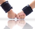 Two hands wearing black colored wrist weights or wrist bands isolated on white along with its reflection also. Royalty Free Stock Photo