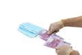 Two hands in white protective gloves buy a pack of blue medical masks for money with 500 Euro banknotes. Concept of buying a mask Royalty Free Stock Photo