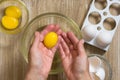 Two hands of woman holding raw chicken yolk after egg separation