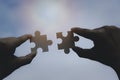 Two Hands of woman trying to connect puzzle piece with sunrise background. Jigsaw wooden against sun rays and sky Royalty Free Stock Photo