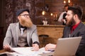 Two handsome bearded businessmen reaching to an agreement during their meeting in a coffee shop. Royalty Free Stock Photo
