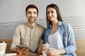 Two handsome freelancers sitting in coworking space, drinking coffee and talking about team project. Man and woman Royalty Free Stock Photo