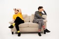 Two handsome guys had a fight while sitting on opposite sides of the sofa. Group of friends are sitting on a soft couch Royalty Free Stock Photo