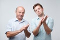 Two mature men smiling and clapping hands. Son and father approving their wifes choice Royalty Free Stock Photo