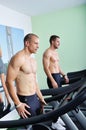 Two handsome men in gym running on the ergometer Royalty Free Stock Photo