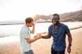 Two handsome multiethnic male friends having a good time together at the beach, smiling, talking, having fun. Summer day. Royalty Free Stock Photo