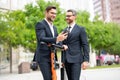 Two handsome young businessman using phone and standing on the street outdoor. Portrait of a smiling businessmen in Royalty Free Stock Photo