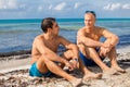 Two handsome young men chatting on a beach Royalty Free Stock Photo