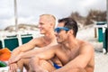 Two handsome young men chatting on a beach