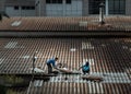 Two handyman workers repairing tiles on the damaged factory roof