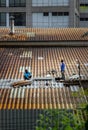 Two handyman workers repairing tiles on the damaged factory roof