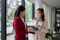 Two happy Asian businesswomen are talking and discussing work in an office corridor Royalty Free Stock Photo