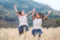 Two happy asian child girls having fun to play and jump in the barley field