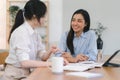 Two happy asian colleagues discussing new project, businesswomen using digital laptop together in office. Royalty Free Stock Photo