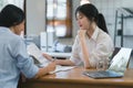 Two happy asian colleagues discussing new project, businesswomen using digital laptop together in office. Royalty Free Stock Photo