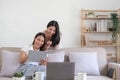 Two happy Asian women best friends in casual wear laughing while working with tablet at home in living room Royalty Free Stock Photo