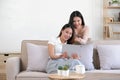 Two happy Asian women best friends in casual wear laughing while working with tablet at home in living room Royalty Free Stock Photo